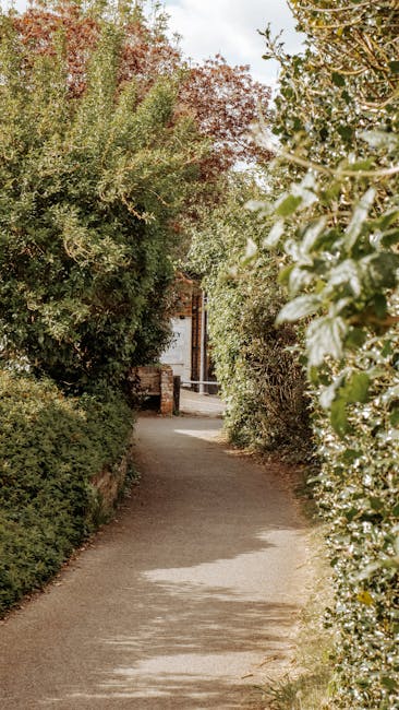 A charming front garden of a red-brick house featuring a bright blue front door with a semi-circular white arch above it. The entrance is framed by lush green foliage, including climbing plants with b